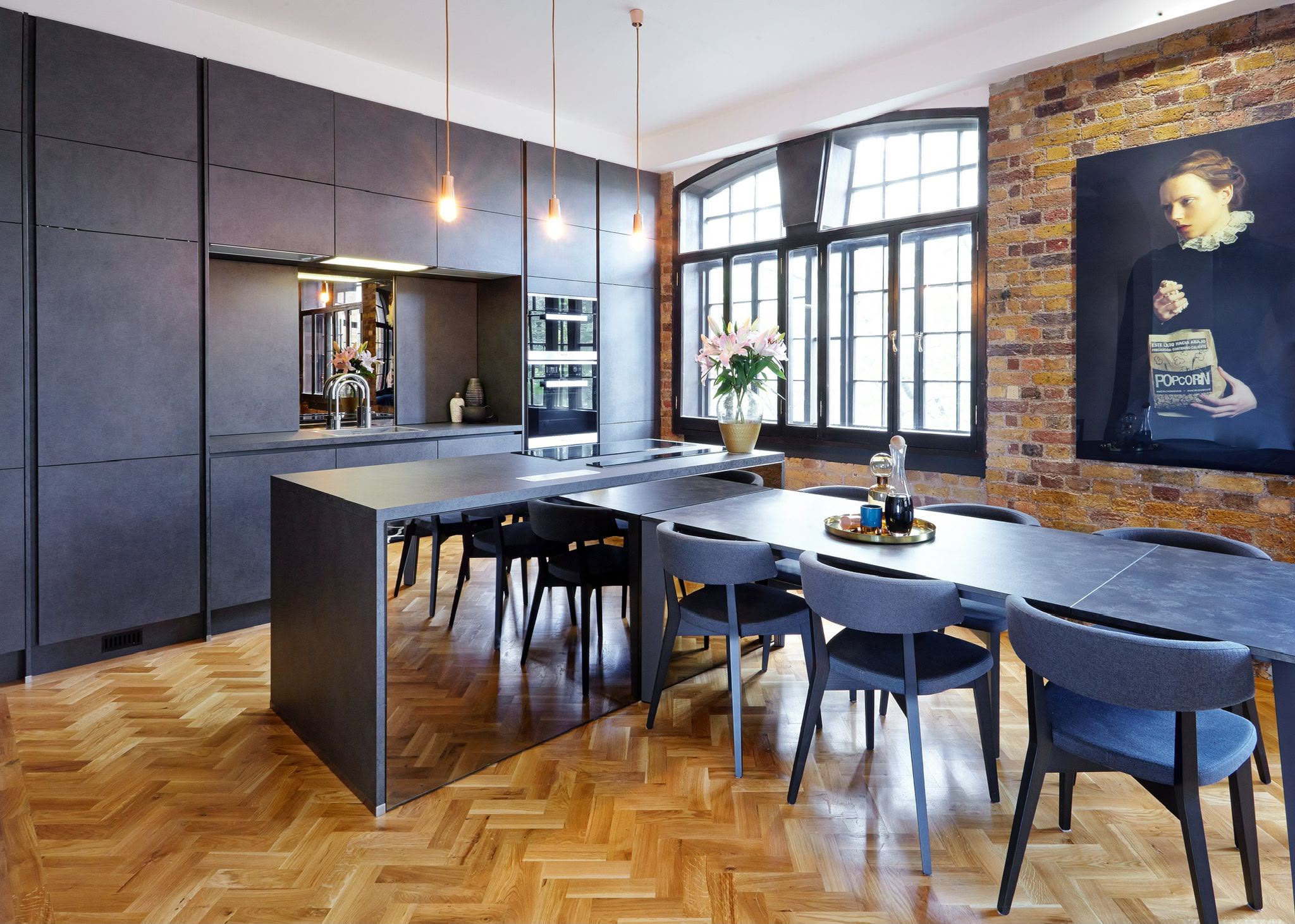 Dark mirrored kitchen island in an industrial-style open-plan kitchen
