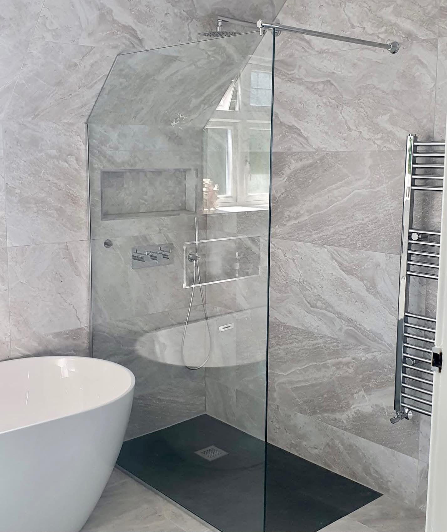 Frameless walk-in shower screen in a grey marble bathroom with freestanding bath
