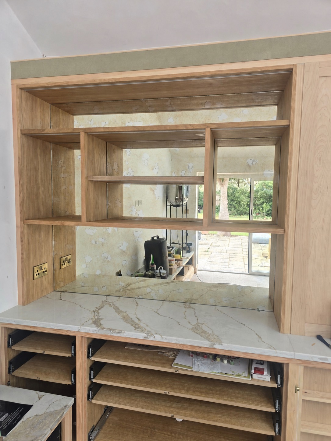 Framed mirror and glass shelves fitted into a custom oak dresser with marble worktop