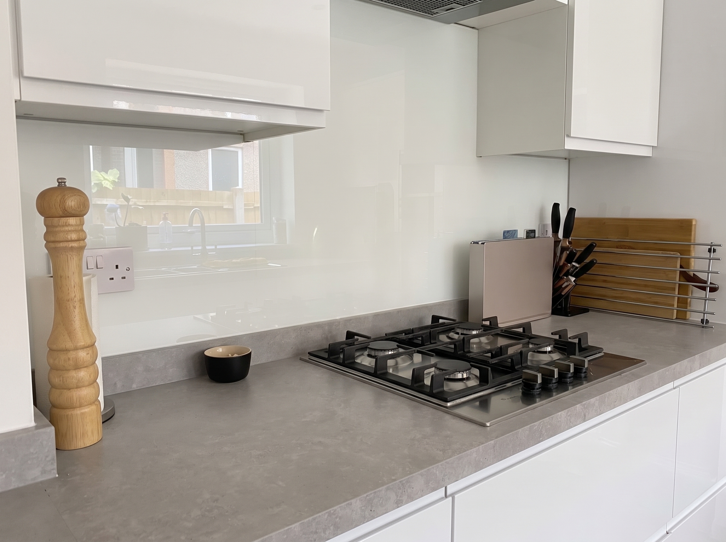 Light grey back-painted splashback with shaped upstand to the extractor